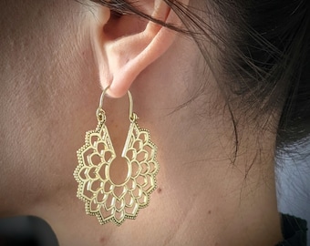 May include: Gold hoop earrings with a delicate, intricate mandala design. The earrings are lightweight and dangle from the earlobe.