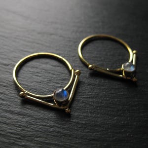 May include: Two gold rings with a moonstone accent. Each ring has a V-shaped design with a single moonstone set in the centre.