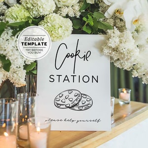 May include: A white sign with black text that reads "Cookie Station" and a drawing of two chocolate chip cookies. The sign also says "Please help yourself".