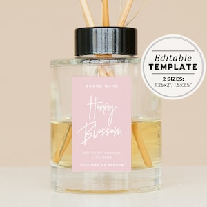 Op de afbeelding: Een heldere glazen diffuserfles met een zwarte dop en een roze label waarop "Honey Blossom" staat. Bovenaan staat "BRAND NAME" en onderaan "NOTES OF VANILLA - PEONIES DIFFUSER DE PERFUM". Het label is bewerkbaar en verkrijgbaar in twee maten: 1,25 x 2 inch en 1,5 x 2,5 inch.
