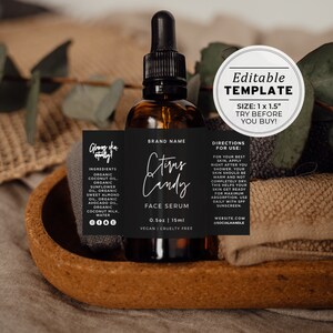 Op de afbeelding: Een zwart-wit label met de tekst "Citrus Candy Face Serum" op een bruine glazen fles met een zwarte druppelaar. Het label bevat ook de ingrediënten, de grootte en de merknaam. De fles staat op een kurken onderzetter.