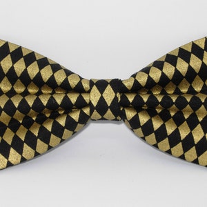 Puede incluir: Una pajarita negra con un patrón de diamantes dorados.