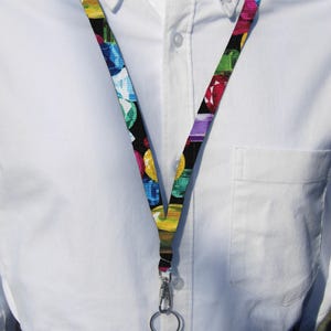 May include: A colorful lanyard with a black background and a variety of colored gemstones. The lanyard has a silver swivel clip and a silver ring.
