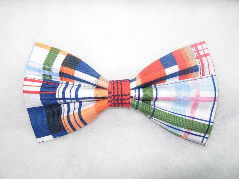 May include: A bow tie with a plaid pattern in shades of blue, orange, green, red, and white.