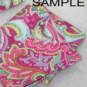 Puede incluir: Un cuadrado de tela con estampado paisley rosa y verde con un borde doblado. La tela tiene un fondo blanco con un estampado paisley rosa, verde y azul.