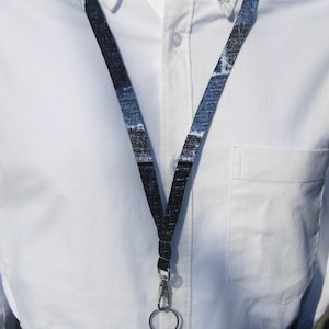 May include: A black and white patterned lanyard with a silver swivel clip and ring.