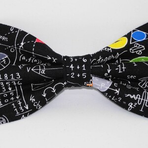 May include: Black bow tie with a white mathematical equation pattern. The pattern includes numbers, symbols, and the words "S VERS", "Vector", "Integers", and "sec".