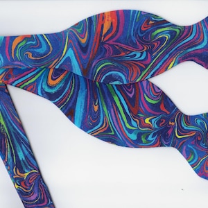 Può includere: Un papillon blu con un motivo astratto a spirale colorato.