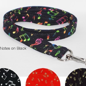 May include: Black lanyard with a repeating pattern of neon-colored musical notes. The lanyard has a silver-colored metal clasp and key ring. The text "Neon Notes on Black" is printed on the image.