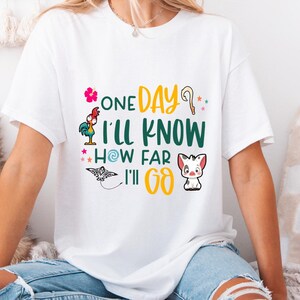 May include: White t-shirt with a graphic print of a rooster, a pig, a seashell, and a star. The text on the shirt reads "One Day I'll Know How Far I'll Go."