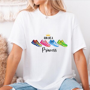 May include: White t-shirt with a graphic of colorful running shoes with bows and the text "Run like a Princess" with a gold crown above the text.