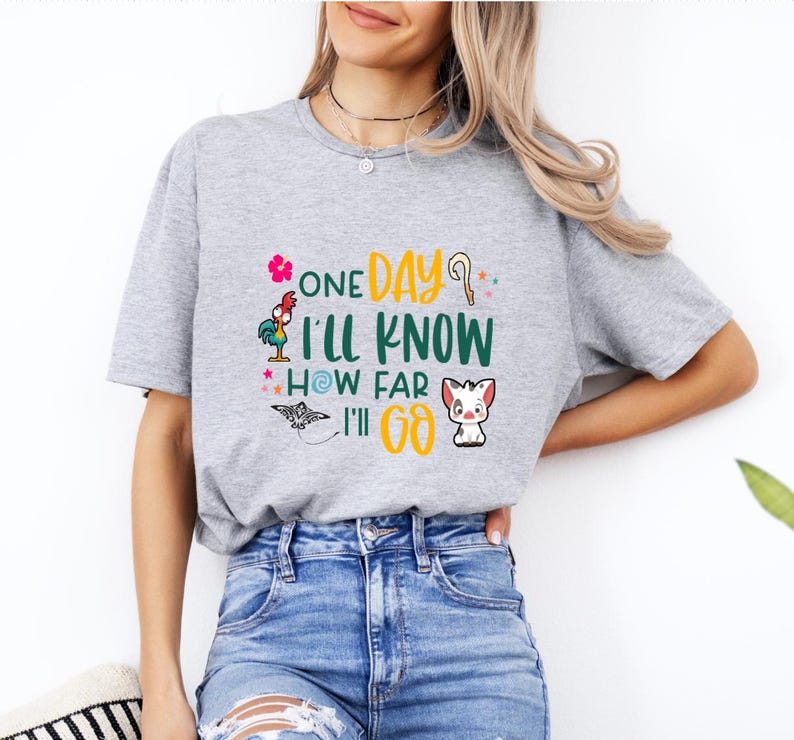 May include: A gray t-shirt with a graphic print of a rooster, a bird, and a pig. The text on the shirt reads "One Day I'll Know How Far I'll Go."