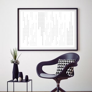 Puede incluir: Una silla de oficina negra con un cojín de asiento gris y un cojín con estampado geométrico en blanco y negro. La silla está sobre un suelo gris frente a una pared blanca con una impresión geométrica enmarcada en negro.