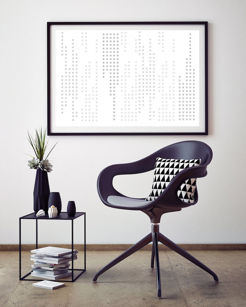 May include: A black office chair with a grey seat cushion and a black and white geometric patterned cushion. The chair is on a grey floor in front of a white wall with a black framed print of a geometric pattern.