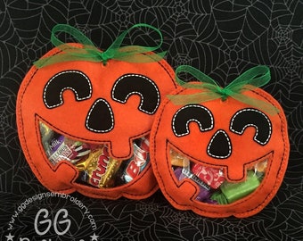 May include: Two orange felt pumpkin treat bags with clear plastic windows. The pumpkins have black felt eyes, noses, and mouths. The bags are tied with green ribbon.