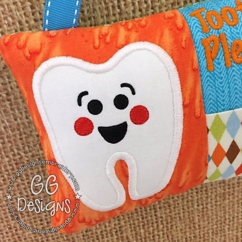 May include: A white tooth pillow with a smiling face, red cheeks, and black eyes. The pillow is made of orange fabric with a white border and is part of a larger patchwork design. The text "Tooth Pillow" is visible in the background.