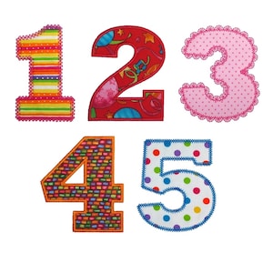 Puede incluir: Un conjunto de números de tela del 1 al 5, cada uno con un diseño único. El número 1 presenta rayas arcoíris, el número 2 tiene un fondo rojo con gráficos temáticos de fiesta, el número 3 es rosa con un borde festoneado, el número 4 tiene un patrón de mosaico y el número 5 tiene lunares.
