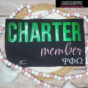 May include: Black t-shirt with green glitter "CHARTER" text, pink "member" text, and gray Greek letters "ΨΦΩ".