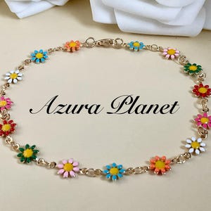 May include: A gold-tone chain bracelet featuring a series of small, multi-coloured enamel daisy charms in shades of pink, blue, white, red, green, and orange. The text Azura Planet is centred within the circular arrangement of the bracelet.