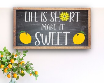 May include: A wooden sign with a black chalkboard background and a white inscription that reads "Life is short make it sweet". The sign is decorated with yellow lemons.