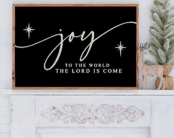 May include: Black and white sign with the word "joy" in a cursive font with silver glitter. The sign also has two silver glitter stars and the text "To the world the Lord is come".
