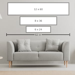 May include: Three rectangular frames with white mats and black frames hanging on a white wall above a gray couch. The frames are labeled with their dimensions in inches: 12 x 60, 8 x 36, and 6 x 24. A ruler below the frames indicates a length of 62 inches.