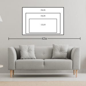 May include: A gray sofa with two button-tufted pillows is positioned below a wall art display. The art features three nested rectangular frames with dimensions labeled as 24x36, 18x30, and 12x24 inches. The overall width is labeled as 62 inches.