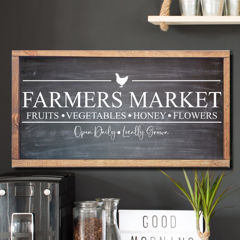 K&ouml;nnte beinhalten: Ein rustikales Schild aus Holz mit einem Holzrahmen und wei&szlig;em Text, der "Farmers Market Fruits Vegetables Honey Flowers Open Daily Locally Grown" lautet, mit einer wei&szlig;en Silhouette eines Huhns &uuml;ber dem Text.