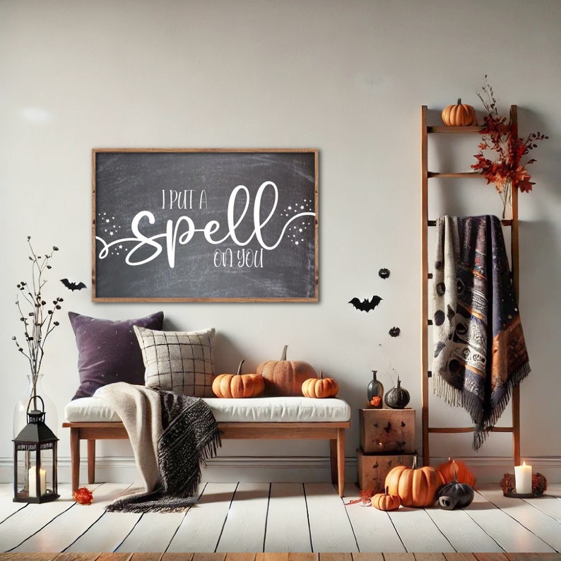 K&ouml;nnte beinhalten: Ein schwarzes Schild aus Schiefer mit wei&szlig;em Text, der "I put a spell on you" lautet. Das Schild h&auml;ngt an einer wei&szlig;en Wand &uuml;ber einer Holzbank mit Kissen und einer Wolldecke. Auf der Bank und dem Boden stehen K&uuml;rbisse und andere Halloween-Dekorationen.