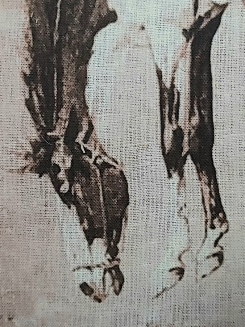 May include: A close-up of a black and white image of two horses' legs printed on a white fabric background.