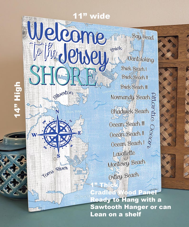Puede incluir: Un letrero de madera de 35,5 cm por 27,9 cm con un mapa azul y blanco de la costa de Jersey. El letrero tiene el texto "Welcome to the Jersey Shore" en letras azules y blancas. Una br&uacute;jula se encuentra en el centro del mapa. El letrero tiene un grosor de 2,5 cm y est&aacute; listo para colgar con un colgador de dientes de sierra o para apoyarse en un estante.