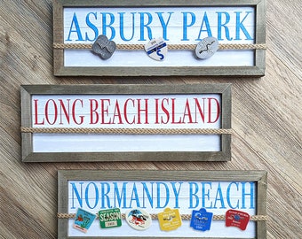 Può includere: Tre cartelli in legno con corda e ciondoli in metallo. I cartelli recitano "Asbury Park", "Long Beach Island" e "Normandy Beach".