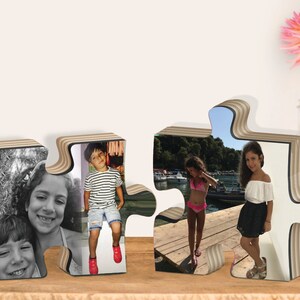 May include: Two wooden puzzle pieces with photos of children. The left piece shows two girls, one in black and white and the other in color. The right piece shows two girls in color, one on a dock and the other standing on a dock.