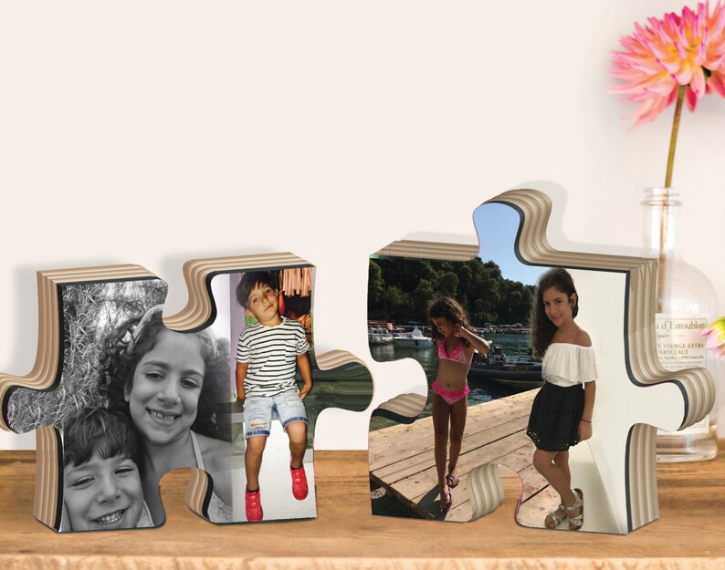 May include: Two wooden puzzle pieces with photos of children. The left piece shows two girls, one in black and white and the other in color. The right piece shows two girls in color, one on a dock and the other standing on a dock.