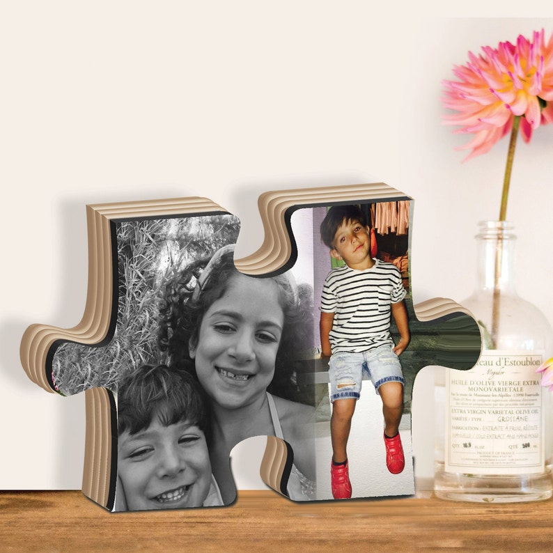 May include: A wooden puzzle frame with two photos of children. The frame is made of layered wood and has a jigsaw puzzle shape. The photos are in black and white and show two children smiling.