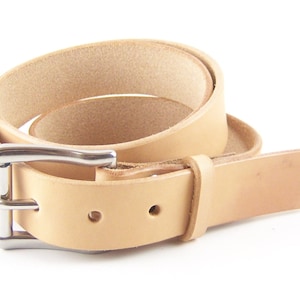May include: A rolled, light tan leather belt with a silver-colored buckle. The belt is made of a single strip of leather and has two holes for adjustment. The buckle is a simple, rectangular design.