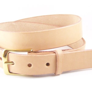 May include: A light tan leather belt with a gold-colored buckle. The belt is rolled up, showing the natural color of the leather. The buckle is a classic rectangular design. The belt has several holes for adjustment.
