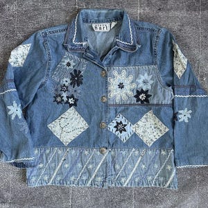 May include: A blue denim jacket with embroidered floral patches and a label that reads "Karen Hart".