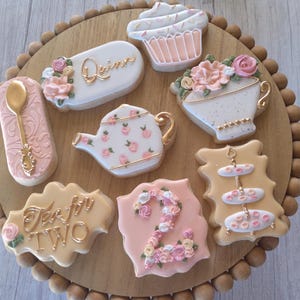 May include: A set of nine decorated sugar cookies with a tea party theme. The cookies feature a teapot, teacup, cupcake, spoon, tiered stand, and the words "Tea for Two" and "Quinn".