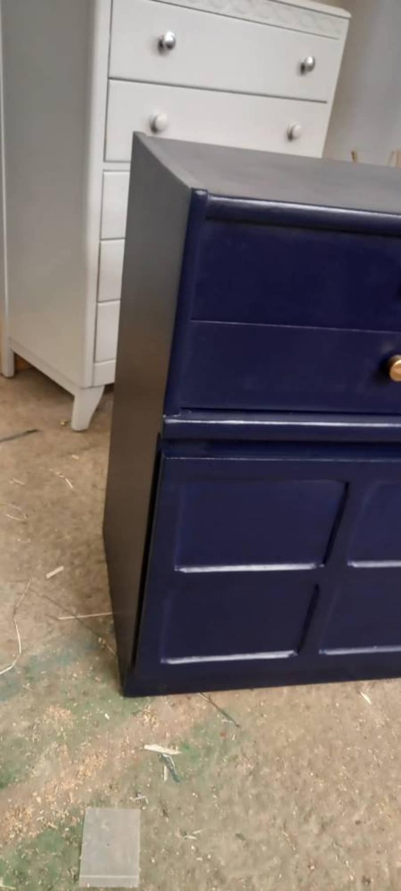 May include: A dark blue dresser with two drawers and a lower cabinet with four doors. The dresser has gold-colored handles.