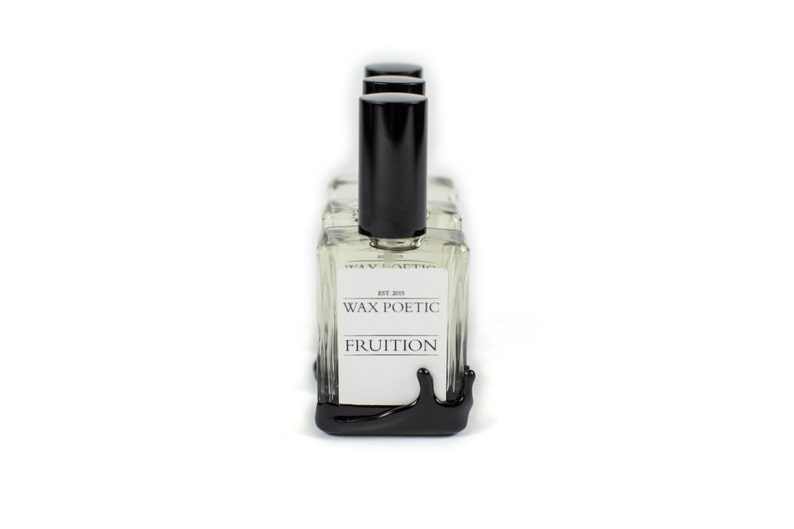 Peut inclure: Quatre flacons en verre transparent avec des bouchons et des &eacute;tiquettes noirs. Les &eacute;tiquettes indiquent "Wax Poetic" et "Fruition". Les flacons sont dispos&eacute;s en rang&eacute;e sur une base noire qui coule.