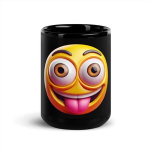 以下が含まれることがあります： 黒いコーヒーマグカップ。3Dの絵文字の顔が描かれています。絵文字は黄色い顔、大きな茶色の目、ピンクの舌です。マグカップは標準的なサイズと形状です。