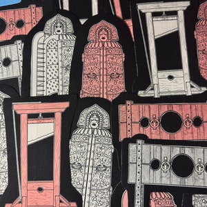 Op de afbeelding: Een verzameling stickers met illustraties van historische martelwerktuigen, waaronder de ijzeren maagd, de guillotine en de schandpaal. De ontwerpen zijn in zwart, wit en roze, met gedetailleerde lijnen en een vintage esthetiek.