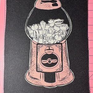 May include: A pink gumball machine filled with white teeth. The gumball machine is on a black background.