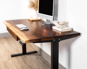 May include: A dark brown wooden desk with a live edge design. The desk has a black metal frame and a built-in drawer. A computer monitor, keyboard, and decorative items are on the desk. The desk is approximately 60 inches long.