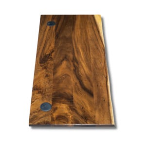 May include: A dark brown wooden desk top with two black grommets. The desk top has a natural wood grain pattern and a front side live edge.