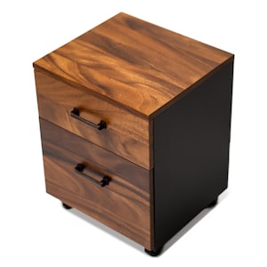 May include: A two-drawer wooden file cabinet with black metal drawer pulls and black painted sides. The filing cabinet is on wheels.