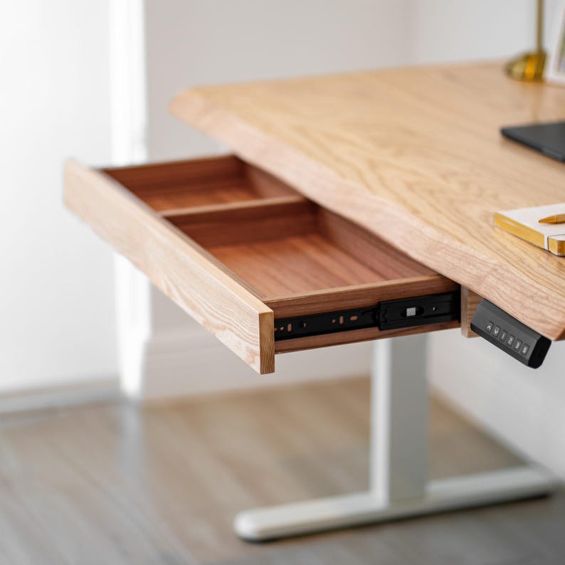 May include: A white oak desk drawer storage. The drawer reveals a two-sectioned interior with a light wood finish.