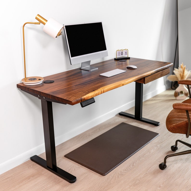 Standing desk with drawer, featuring durable walnut hardwood and a unique live edge. Supported by black dual motor legs for easy height adjustment. A versatile piece of adjustable office furniture.