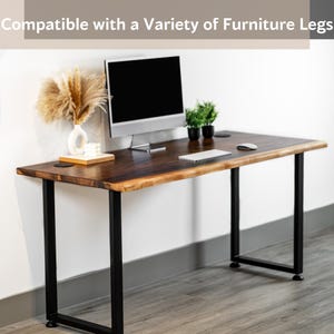 May include: A wooden computer desk top with black metal legs. The desktop has a live edge and is compatible with a variety of furniture legs. The desk is shown with a computer monitor, keyboard, mouse, and plants.